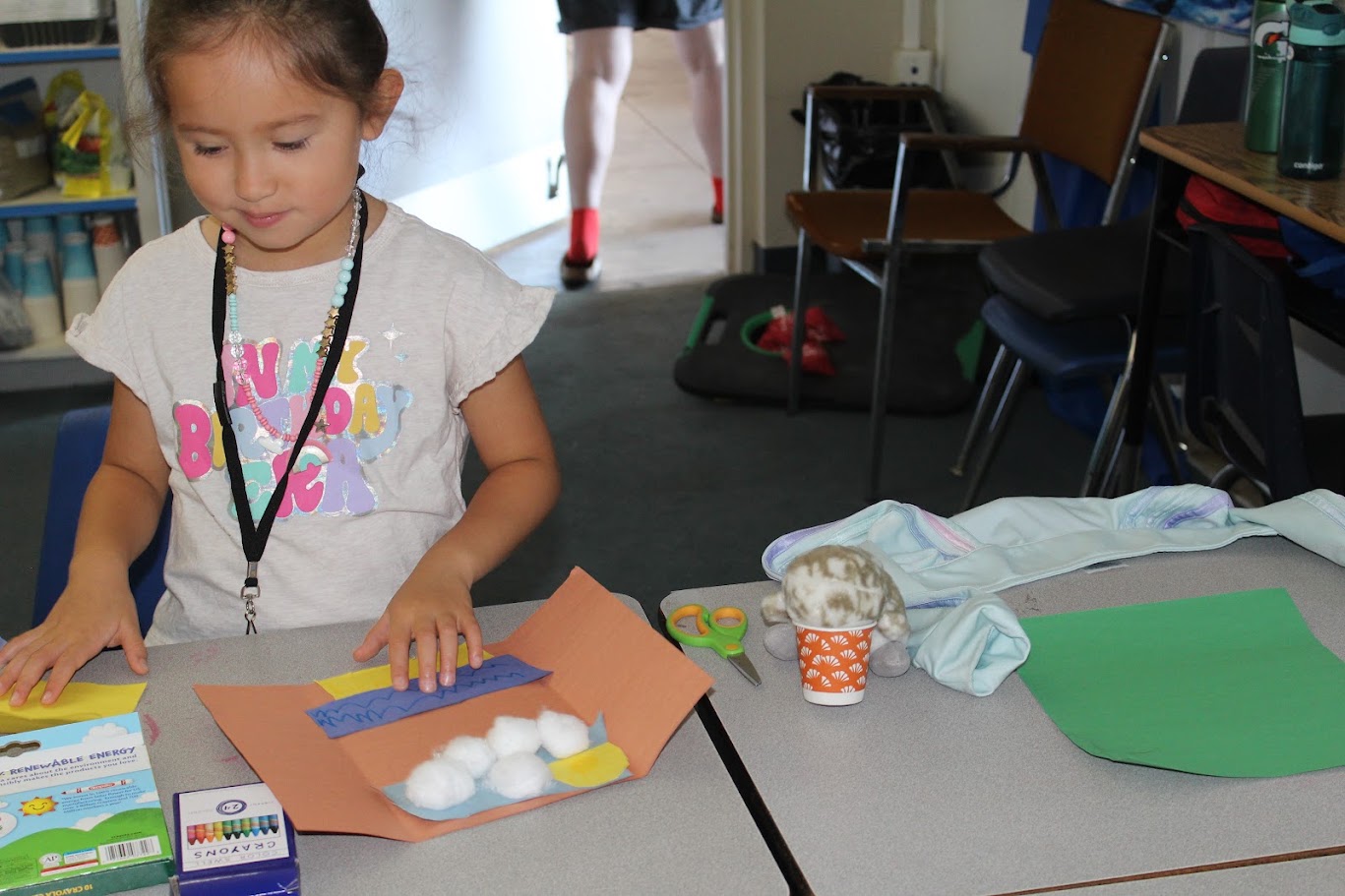 A Junior STEM camper creating a hands-on project with colorful paper and cotton