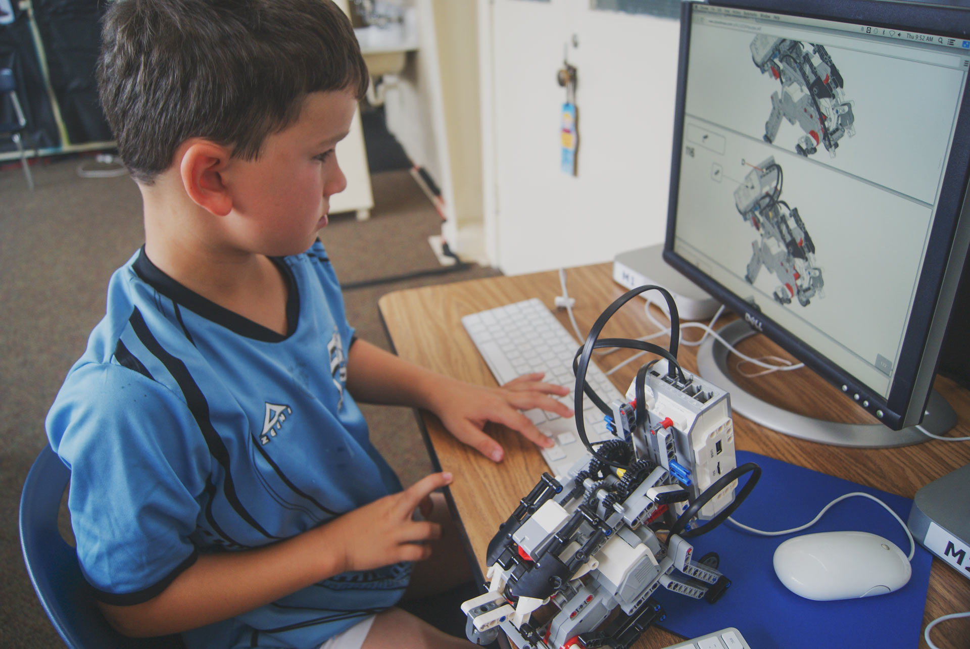 A PlanetBravo camper building and programming a robot at a computer